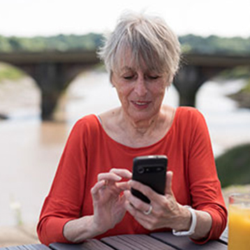 Woman using a Doro smartphone by a river.