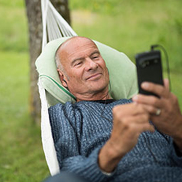 Lasse Holm in a hammock with a Doro smartphone.